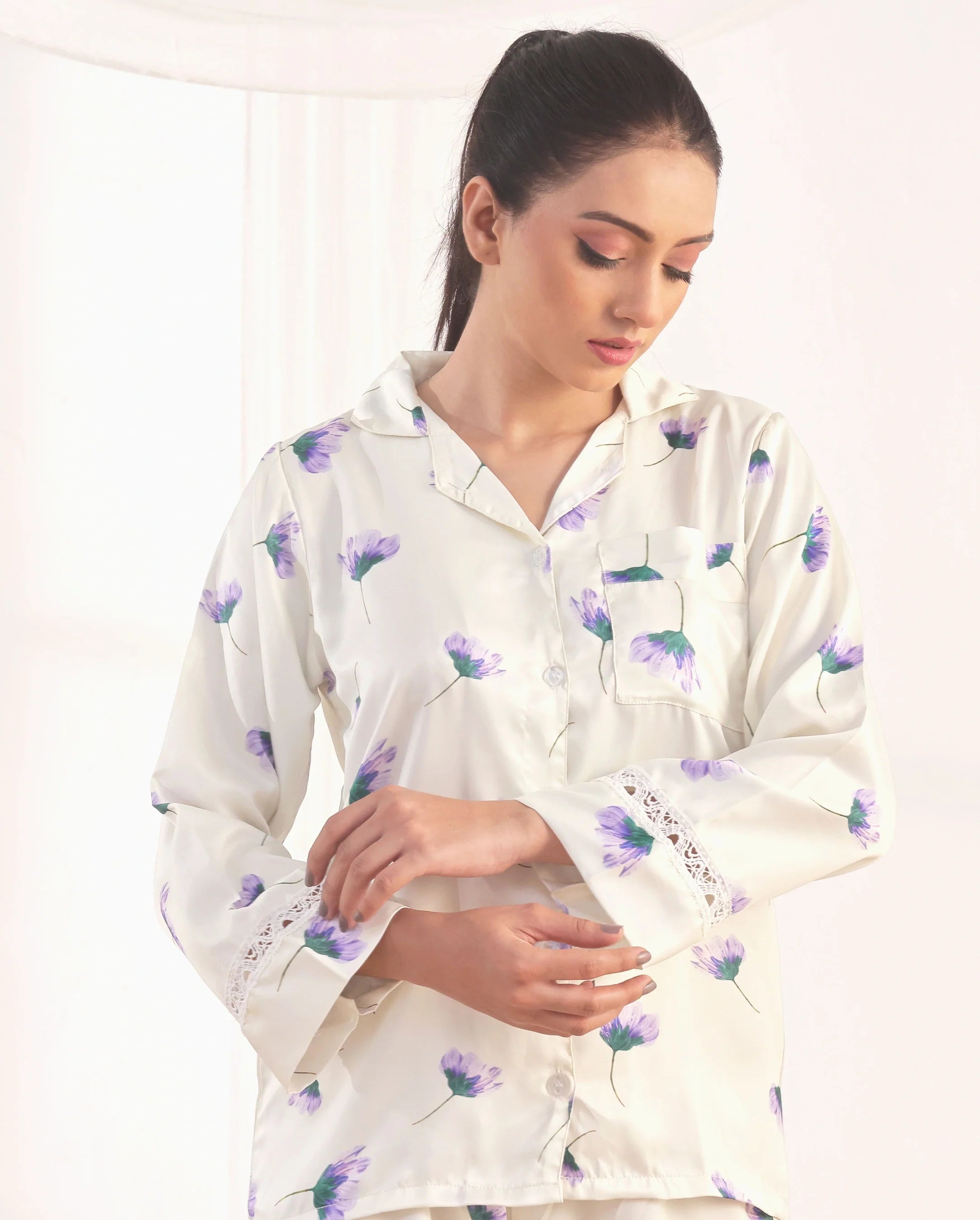Woman wearing a white floral pajama set against a plain background